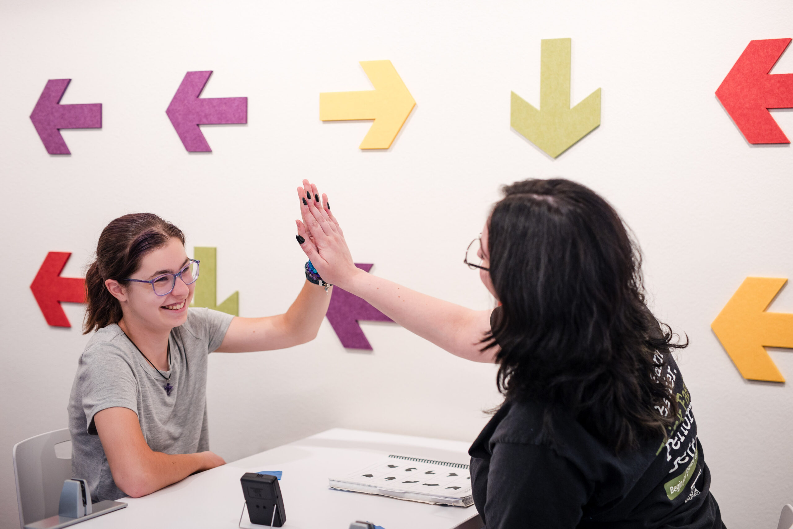 A student and her trainer exchange a high-five after a big win in a brain training procedure. 